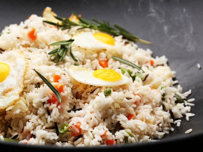 Tasty rice preparing in wok, close-up