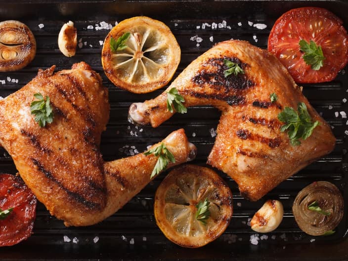 NaCl - brining makes meat juicier - Two grilled chicken legs and vegetables on the grill pan close-up. horizontal view from above