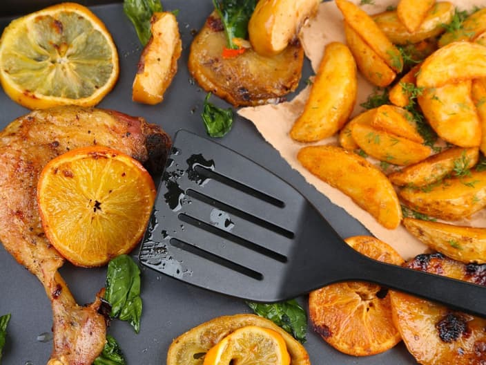 spatula - Homemade roasted chicken drumsticks with fried potatoes and vegetables on pan, isolated on white