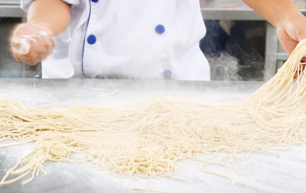 flour and noodle dough - Chef making noodles in the kitchen of cooking school.