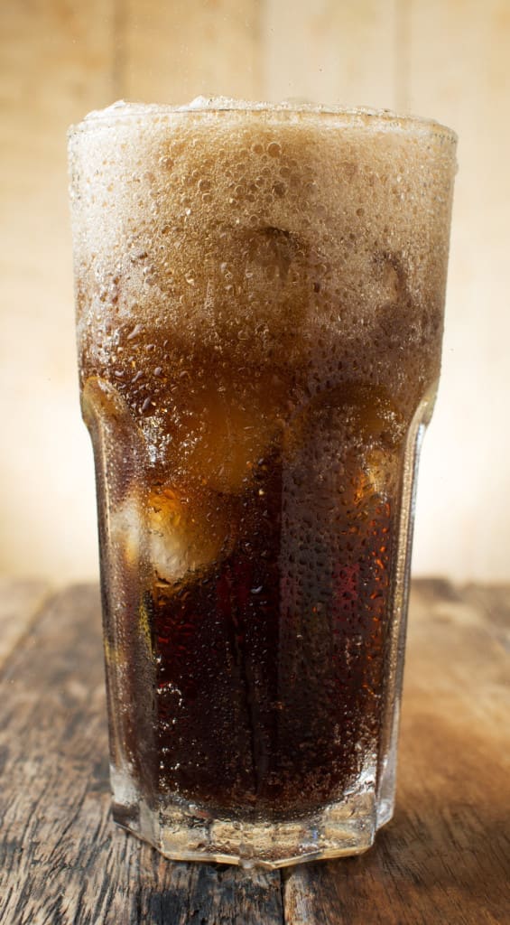 very fizzy soda/soft drink on a wooden background