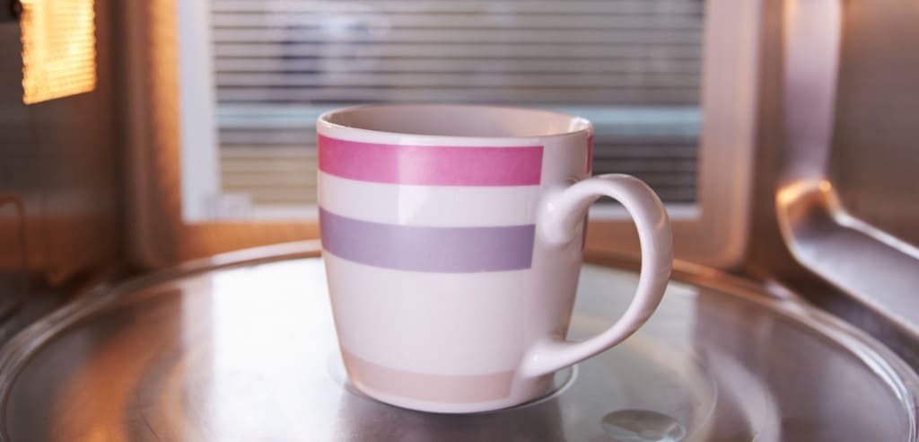 Warming Cup Of tea Inside Microwave Oven