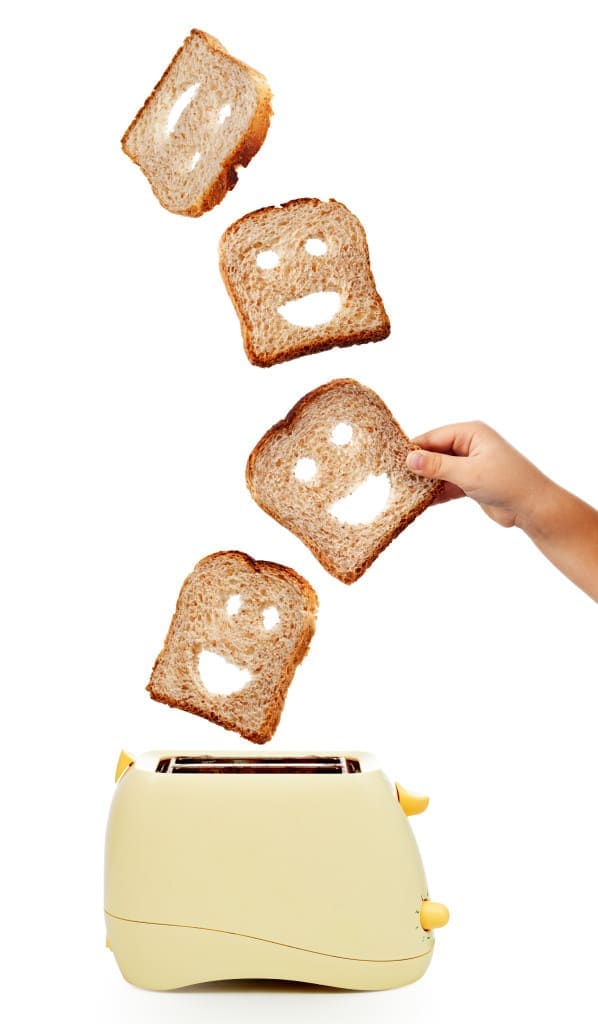 Child hand catches toast bread slices flying out of a toaster