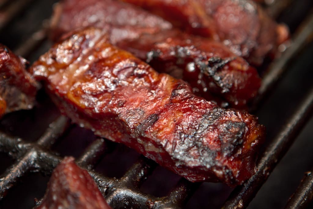 Barbecue beef spare ribs cooking on a grill outdoors in summer