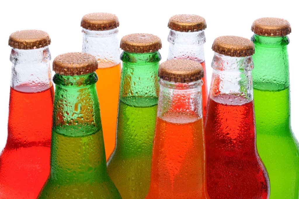 soda bottles - Closeup of several assorted flavors of soda pop. Orange, lemon lime, and strawberry soda bottles necks only over a white background.