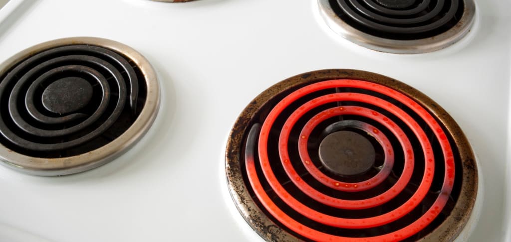 Four electric elements on a stove with one turned on