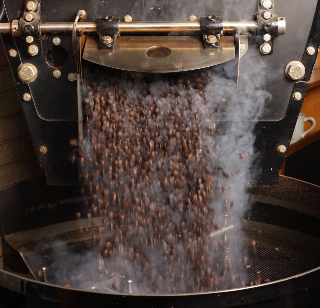 Freshly roasted coffee beans from a roaster being poured into the cooling cylinder. 