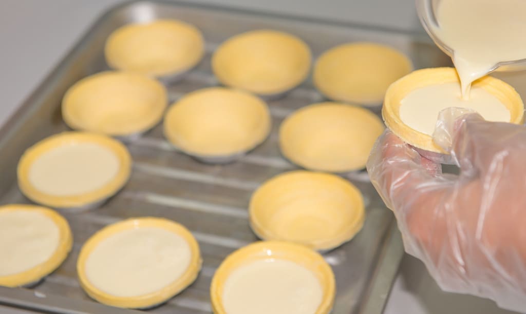 preparing egg tarts for baking