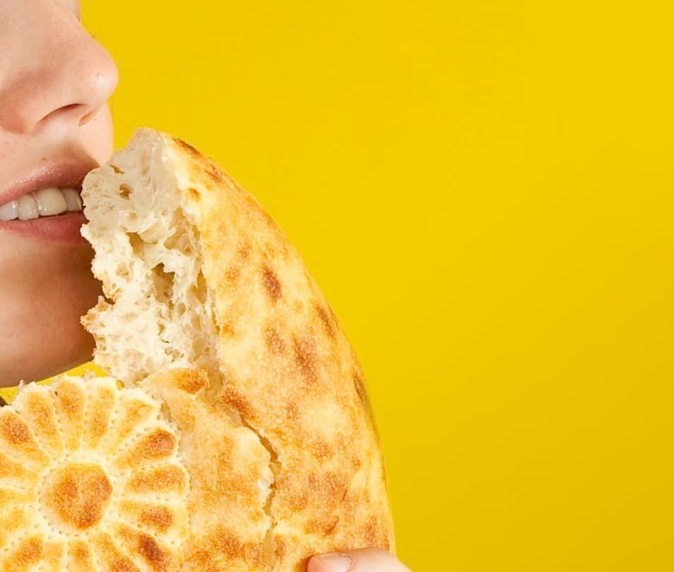 female baker is smelling fresh loaf over yellow