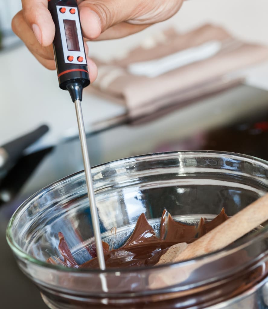 Using a thermometer to temper chocolate - Close Up Of Men's Hand Measuring Chocolate Temperature With Kitchen Thermometer Step 2/7