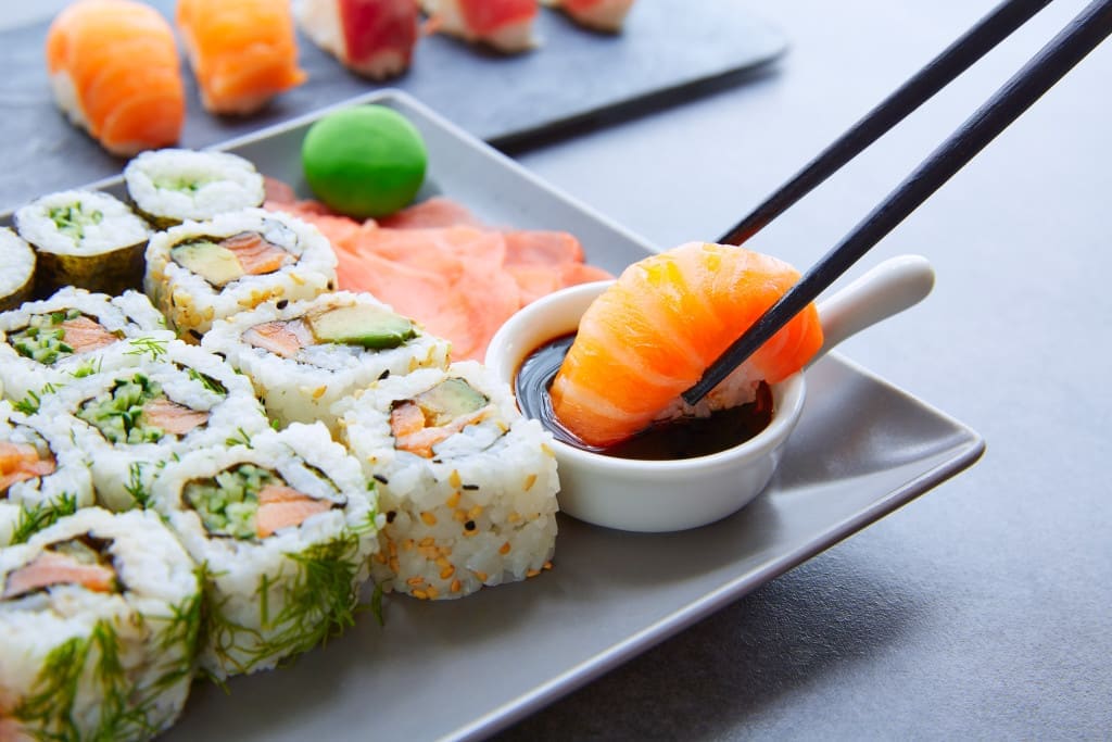 Umami - dipping sushi in soy sauce - Sushi Maki and Niguiri with soy sauce and wasabi with California Roll