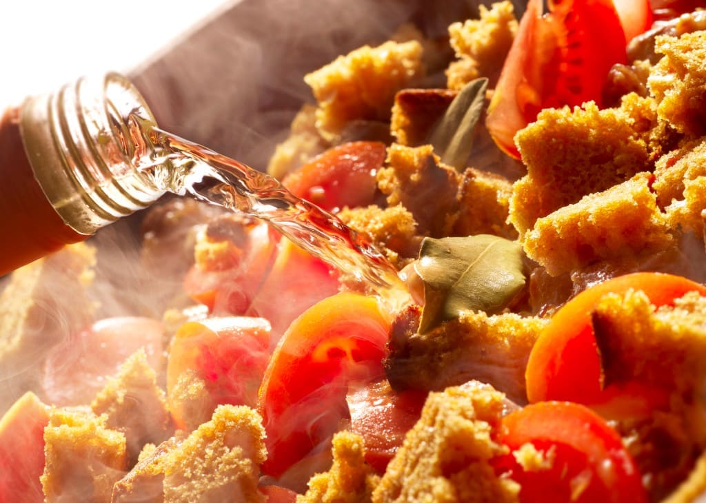 cooking with alcohol - pouring white wine in a cooking pan with steam