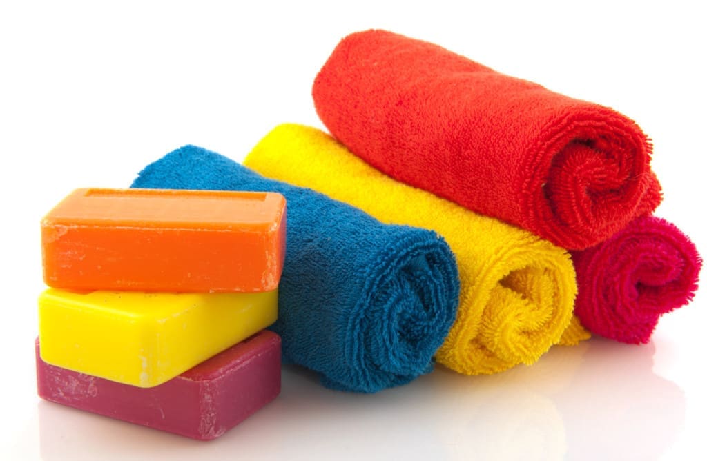 soap is an emulsifier that creates an emulsion of water and grease, making it easy for the former to wash off dirt - colorful rolled towels with bars soap isolated over white