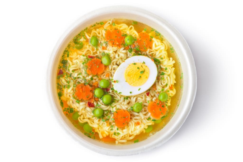 Cup of instant noodles with vegetables. Top view. Isolated on white.